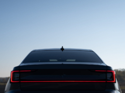 Polestar 2 performance during sunrise from behind with the lights on.